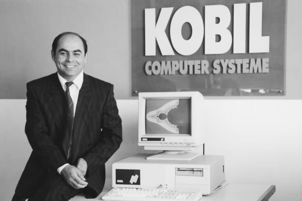 KOBIL founder Ismet Koyun beside an early personal computer in front of a KOBIL Computer Systeme sign