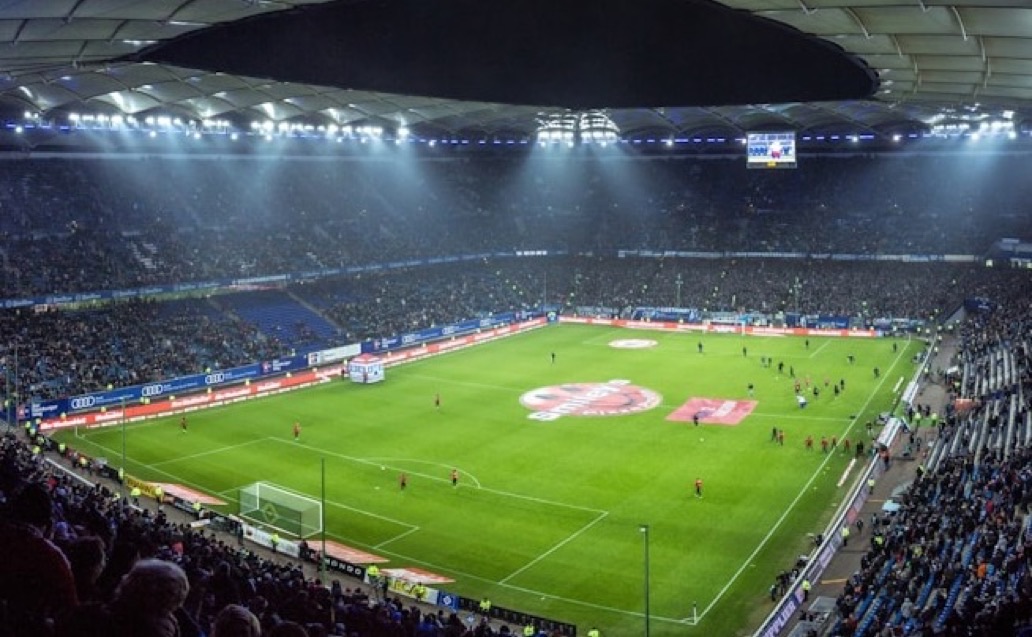Fans watching a floodlit match in a packed stadium